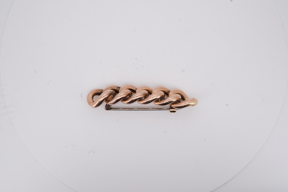 An early 20th century yellow metal and graduated five stone coral bead brooch, with seed pearl spacers, 45mm, together with a yellow metal curb link brooch and a yellow metal (stamped 9c) safety pin. Condition - fair